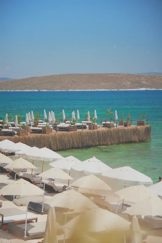Uma Alaçatı plajı — turkuaz koy ve şezlonglar